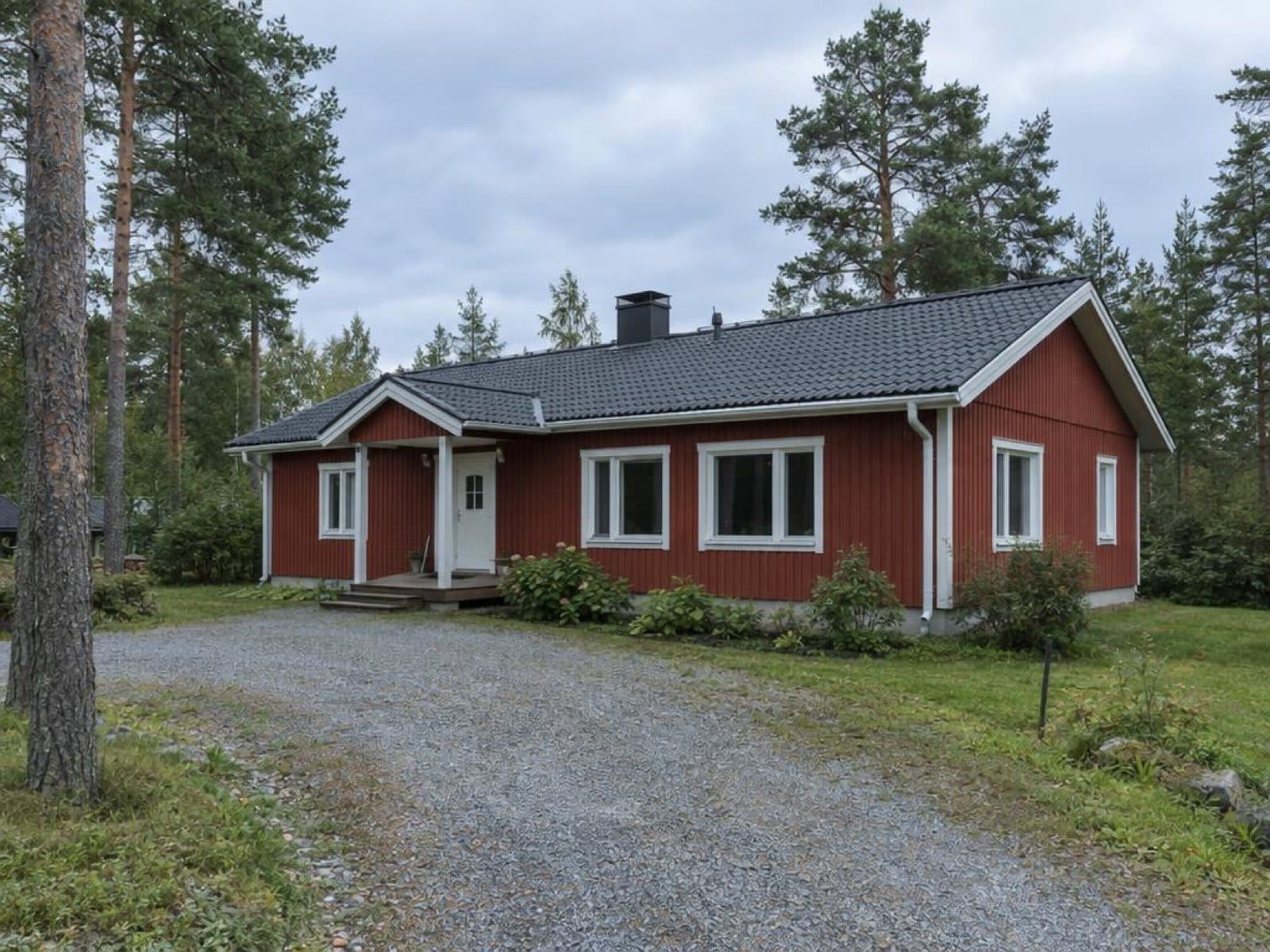 Punainen puinen omakotitalo tasaisessa päivänvalossa