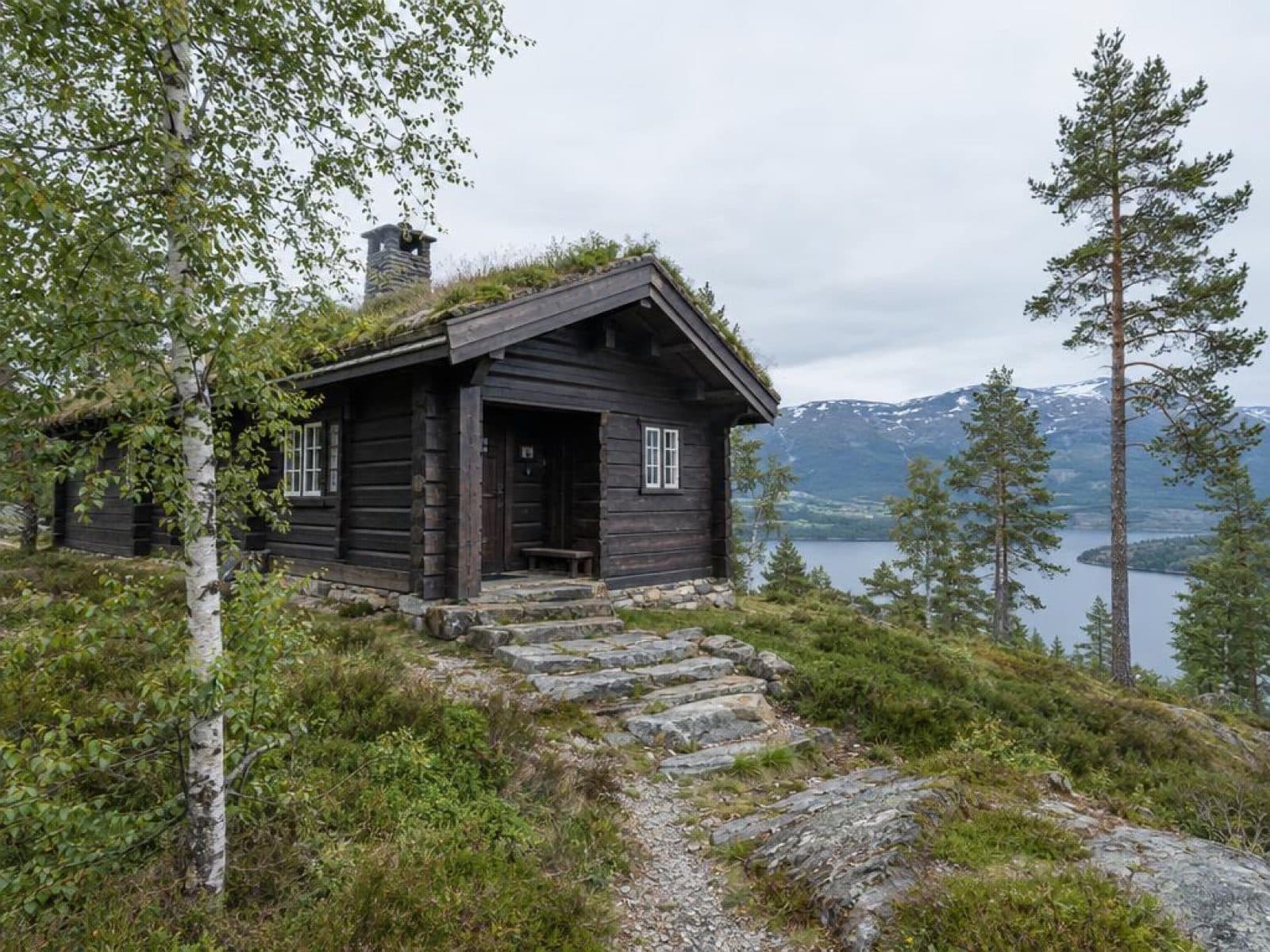 Norsk fjellhytte ved en fjord fotografert midt på dagen