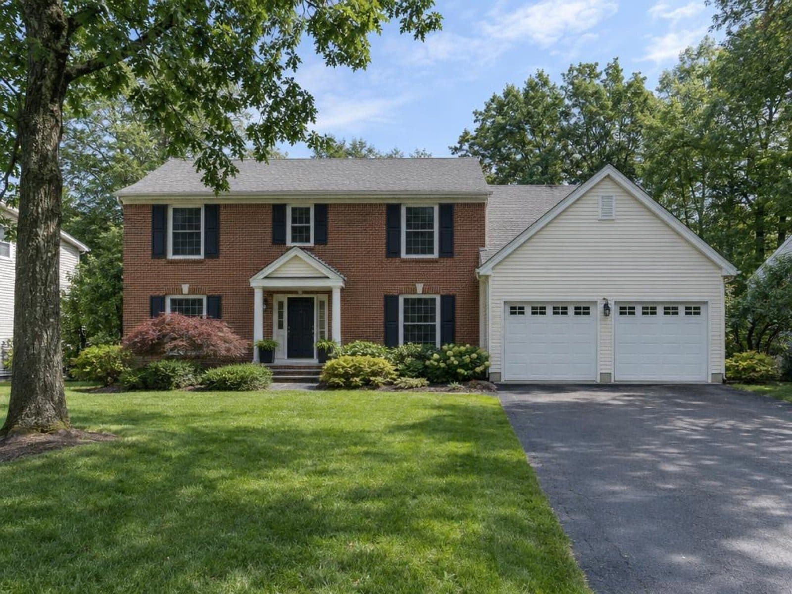 Brick colonial with a two-car garage, photographed in the daytime with unlit windows