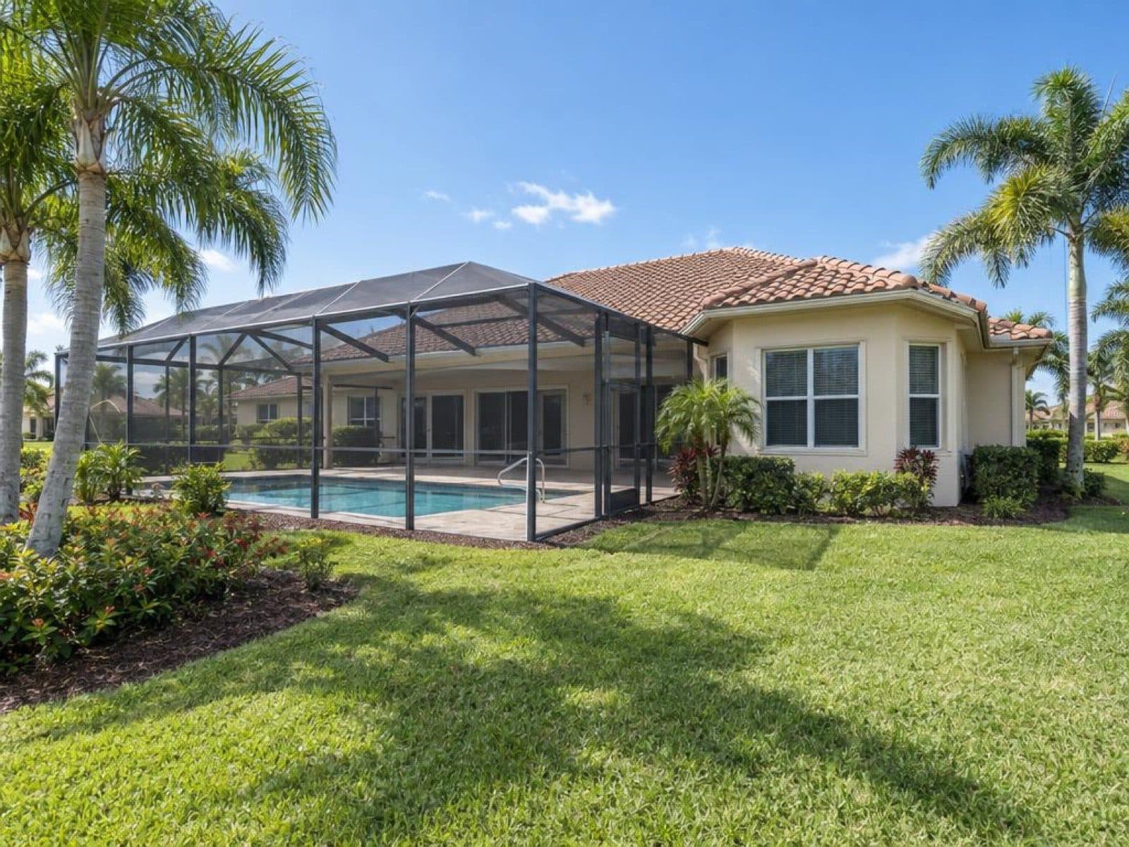 Daytime exterior of a Florida pool home with a screened lanai