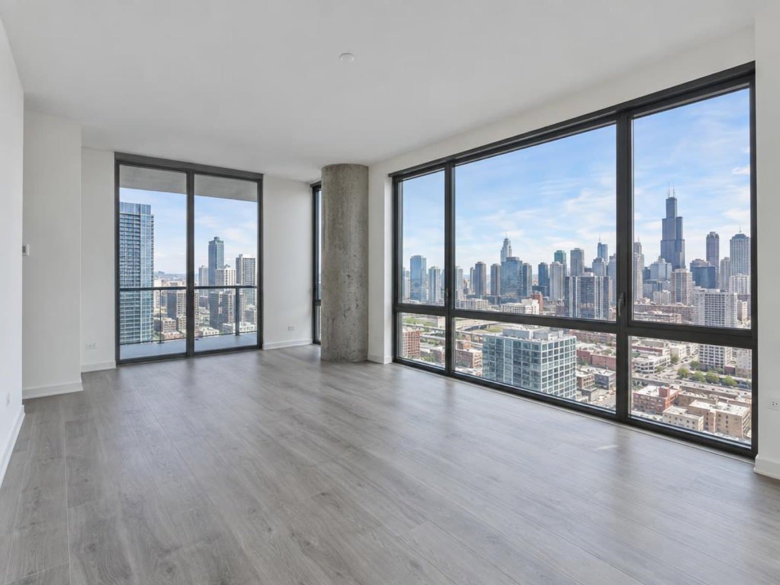 Empty condo living room with floor-to-ceiling windows and a city view