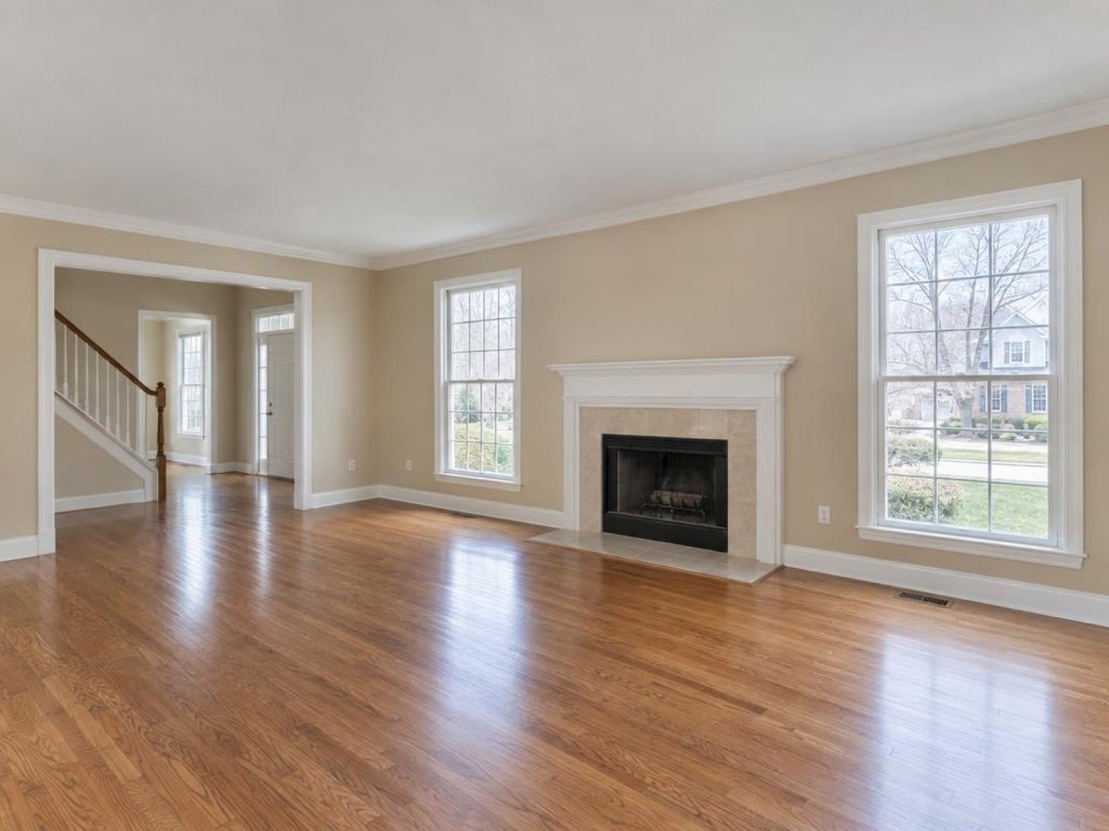 Empty living room with hardwood floors and a fireplace, photographed on a phone