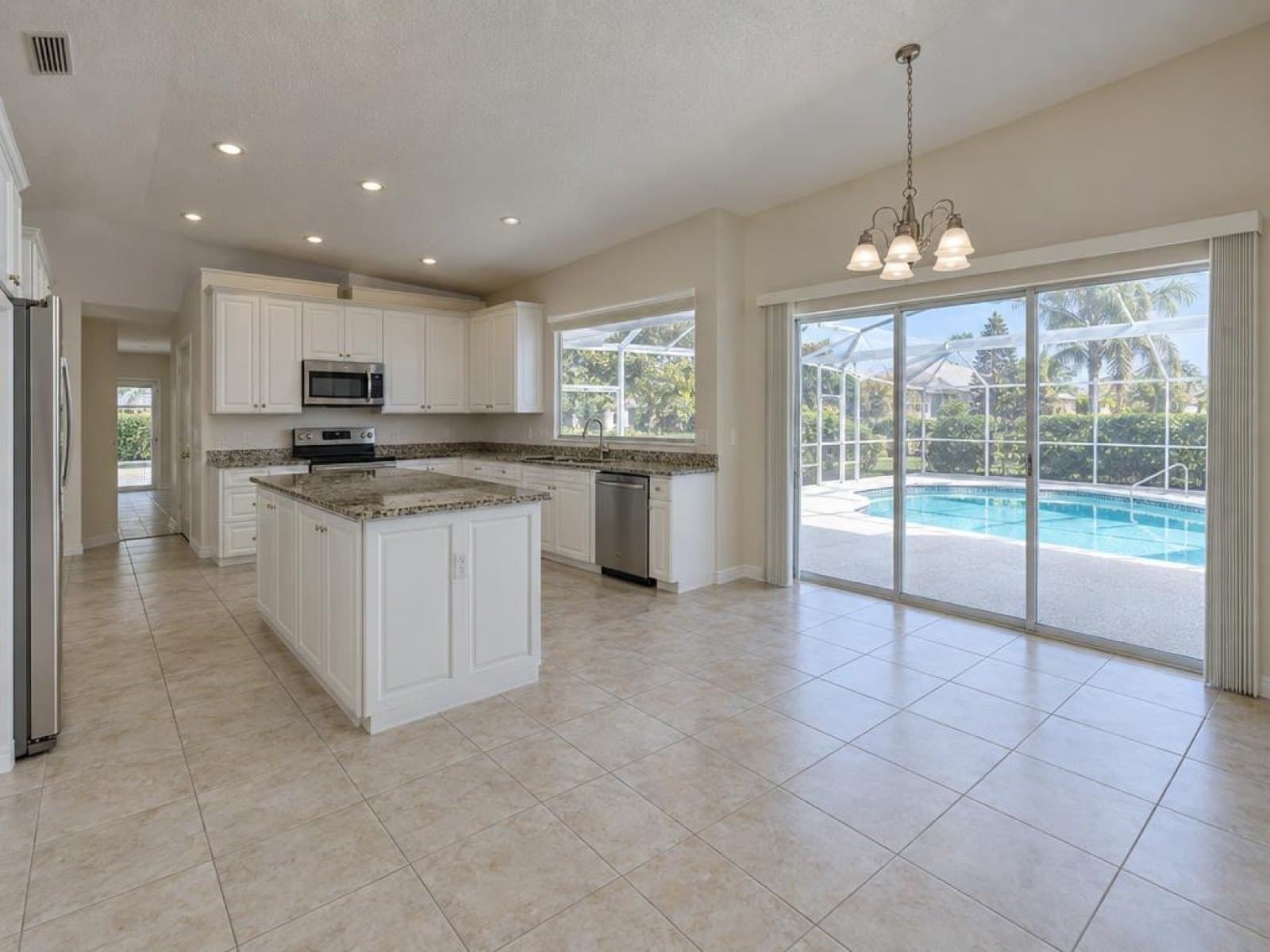 Empty kitchen and dining area opening to a screened pool lanai