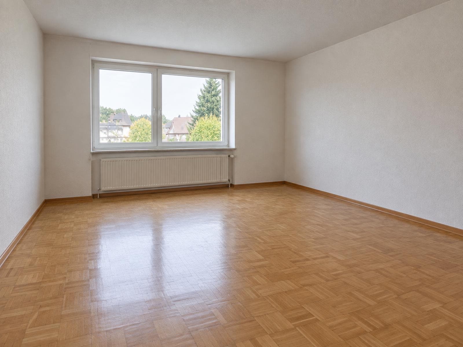 The same living room with all furniture removed, showing the bare walls and floor